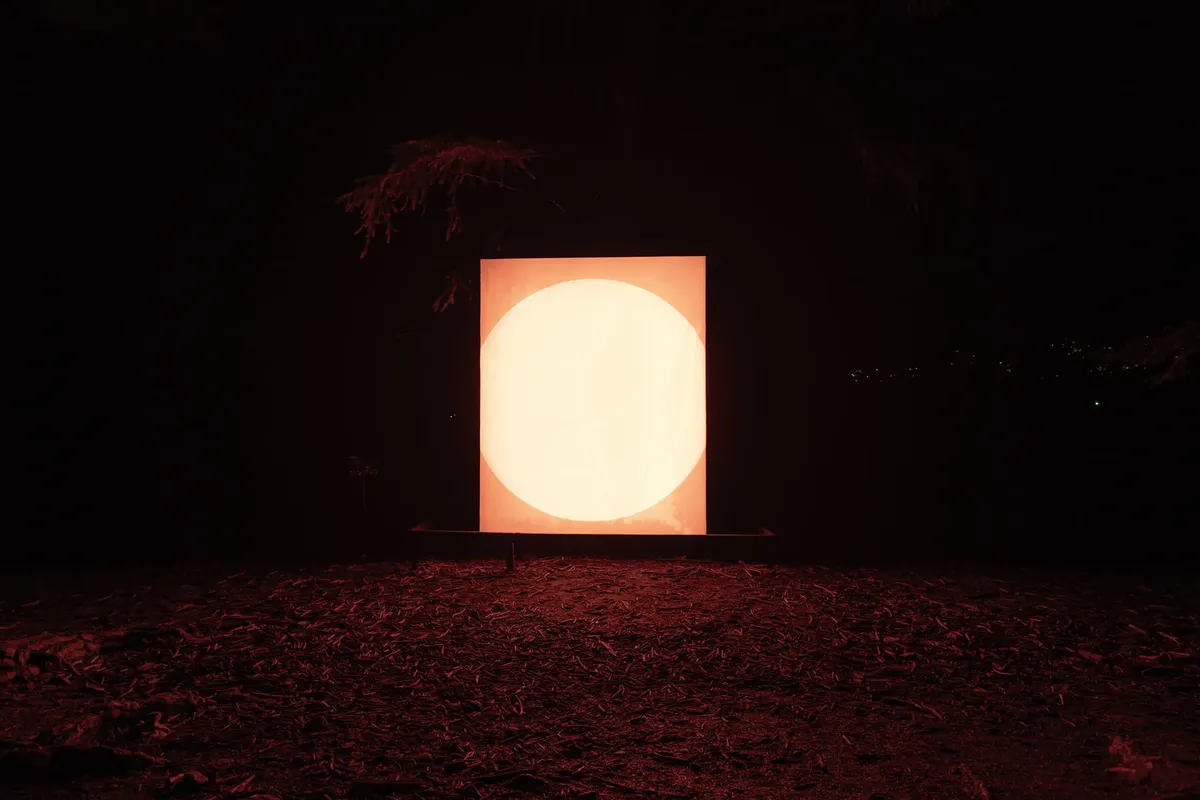 Brightly lit circular art installation against nighttime backdrop in Queenstown, New Zealand.
