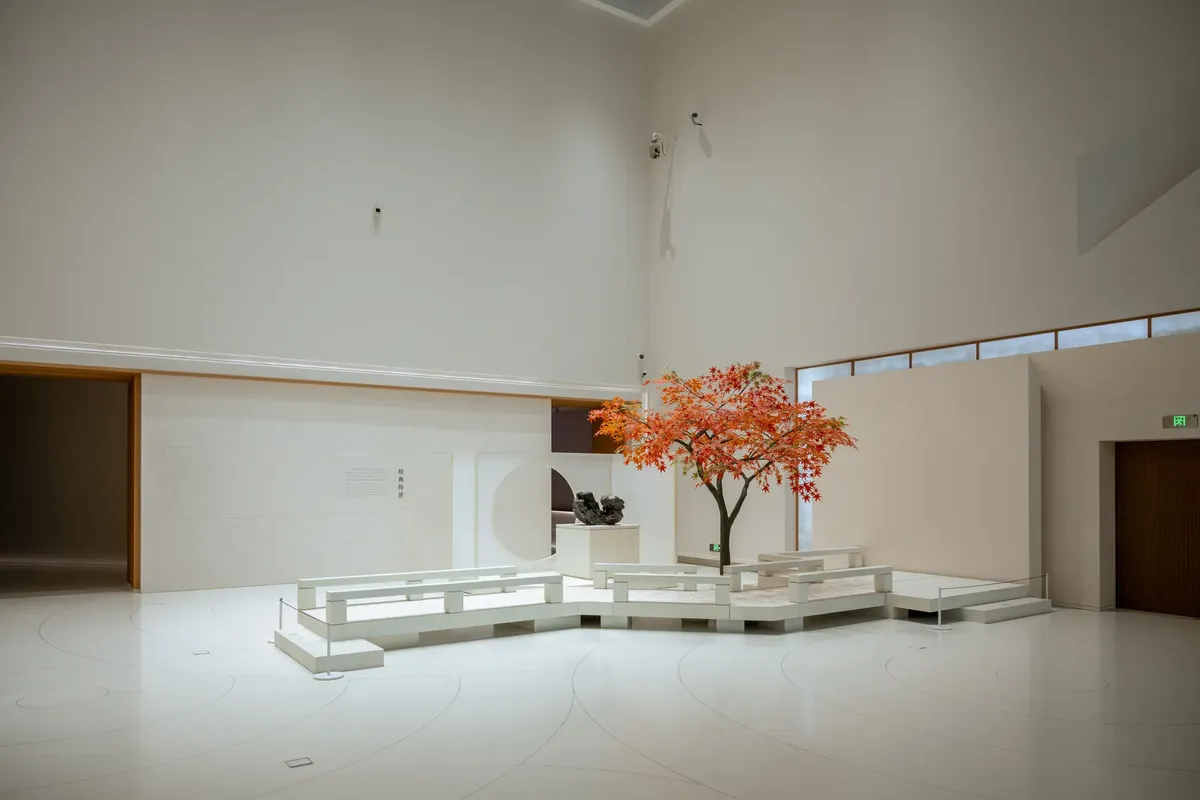 A minimalist indoor art installation featuring a vibrant autumn tree set in a gallery in Shanghai.