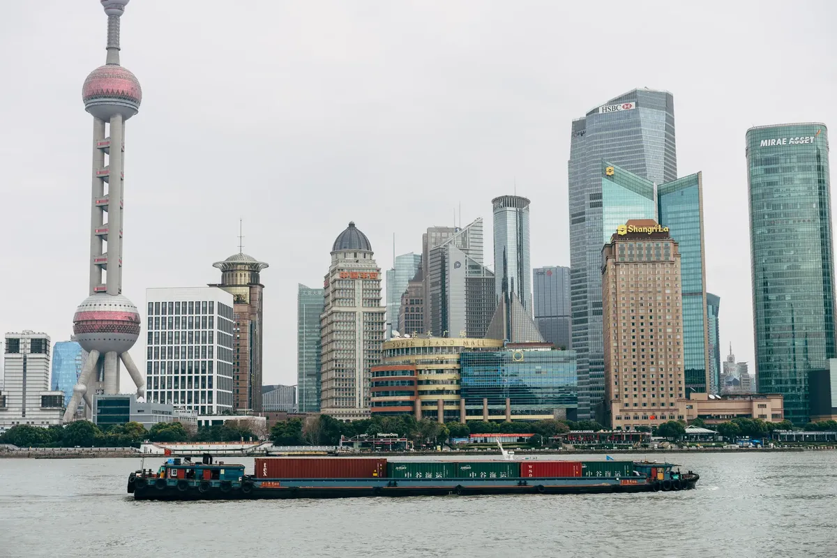 Panoramic view of Shanghai skyscrapers and a cargo boat on Huangpu River, capturing the city's modern architecture.